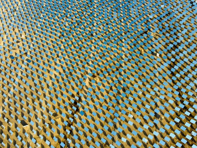 Vista aèria d'un camp massiu d'heliostats i espalls solars en una gran planta d'energia solar.
