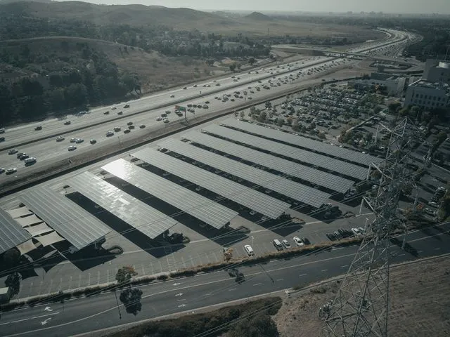 Marquises solars en un aparcament al costat d'una autopista amb tràfics i fums industrials.