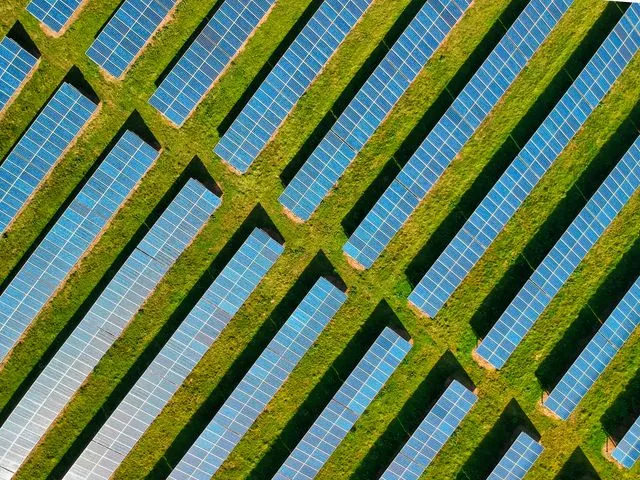 Vista aèria d'un parc solar instal·lat en un camp agrícola amb rengleres de plaques fotovoltaiques.