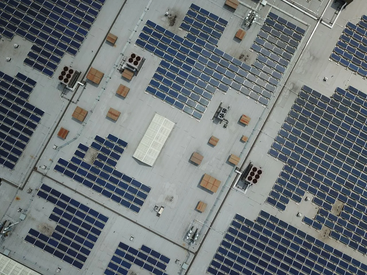 Vista aèria de la coberta plana d'una nau industrial amb una gran instal·lació fotovoltaica comercial.