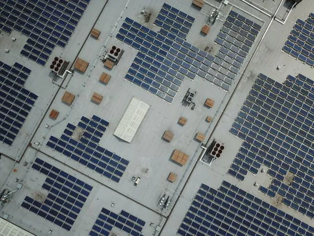 Vista aèria de la coberta plana d'una nau industrial amb una gran instal·lació fotovoltaica comercial.